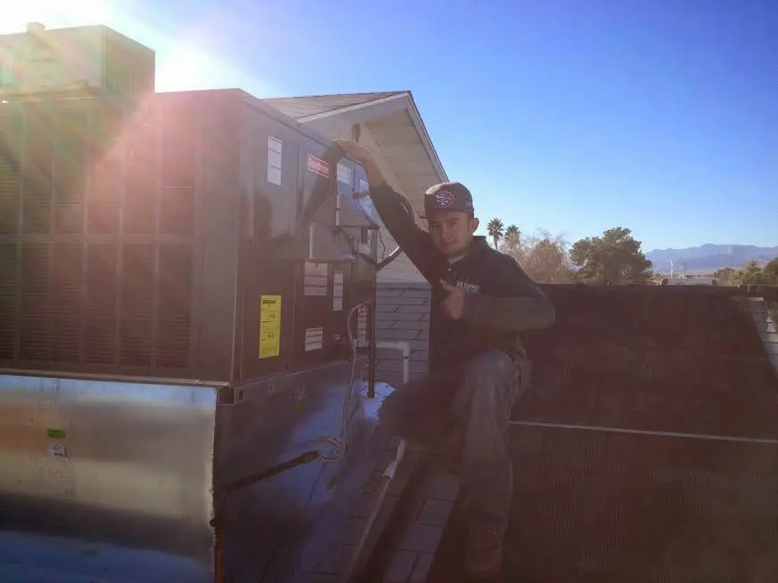 HVAC technician performing Air Duct Cleaning on a rooftop unit in Logan